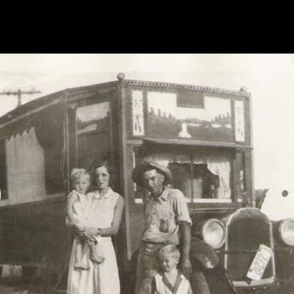 A family of 4 posed in front of a truck.