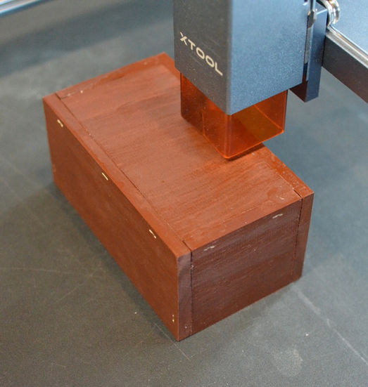 Photograph of a wood box preparing to be laser engraved