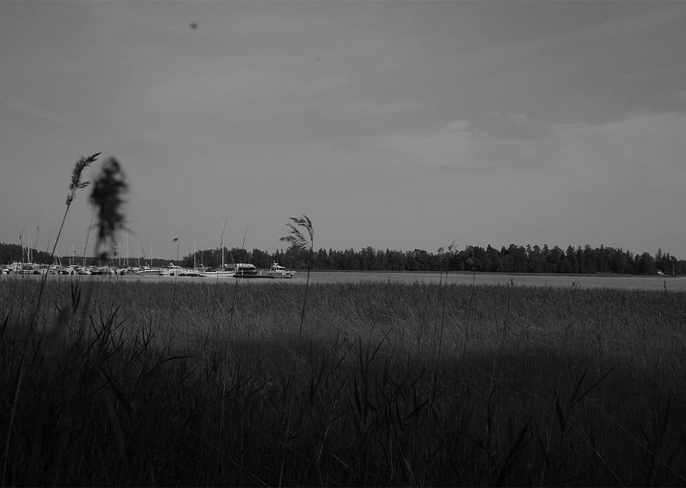 A black and white image of a Finnish lake, boats and forest