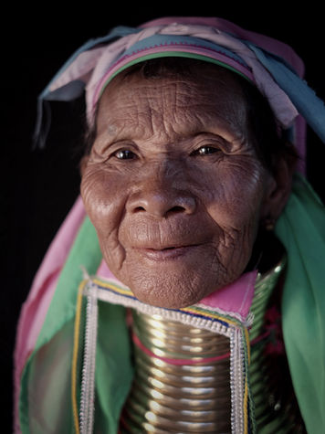Portrait photograph of a Kayan woman from Myanmar wearing traditional neck rings and colourful clothing.