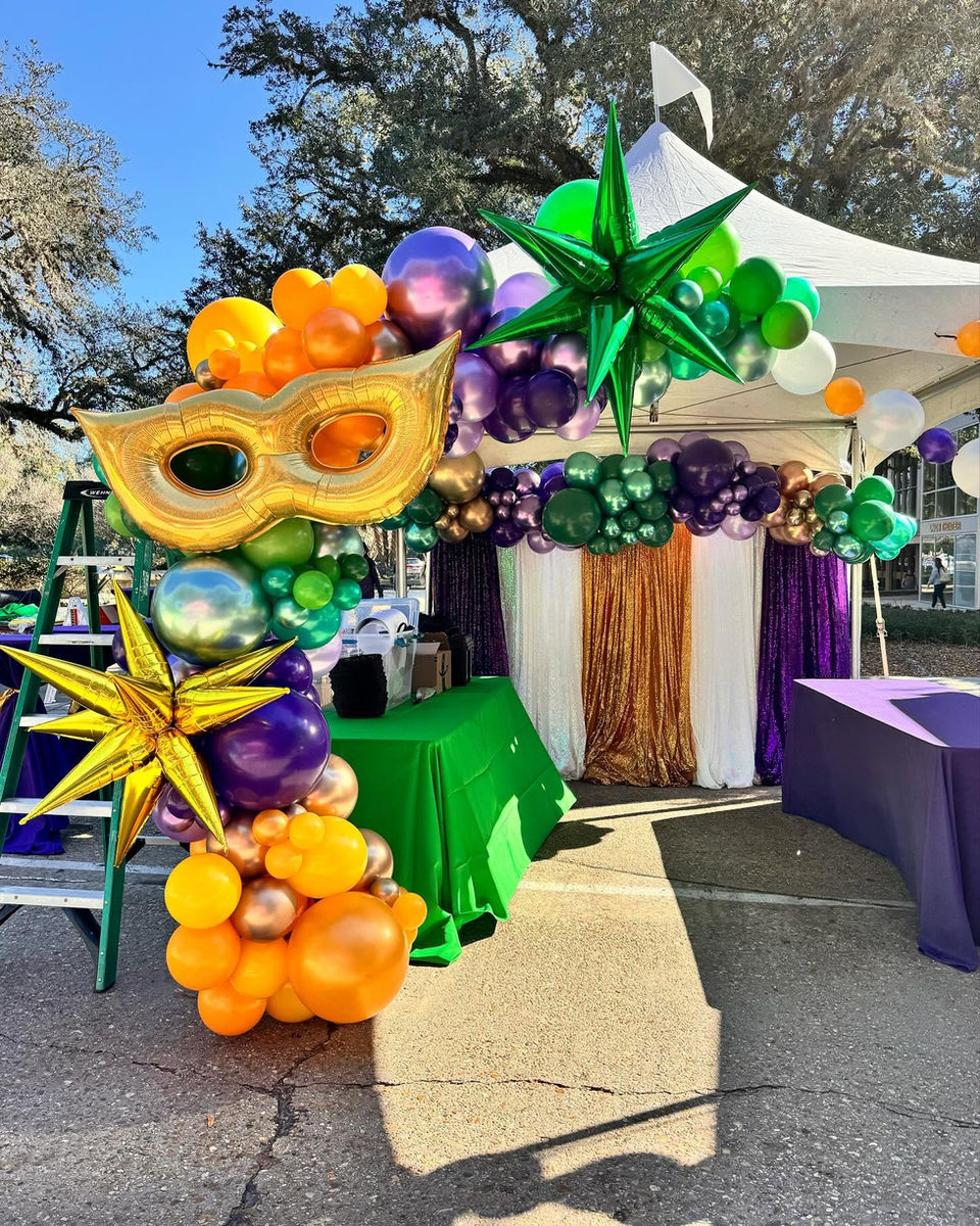 Custom green, yellow and purple balloon garland with a mask for a Mardi gras themed balloon garland