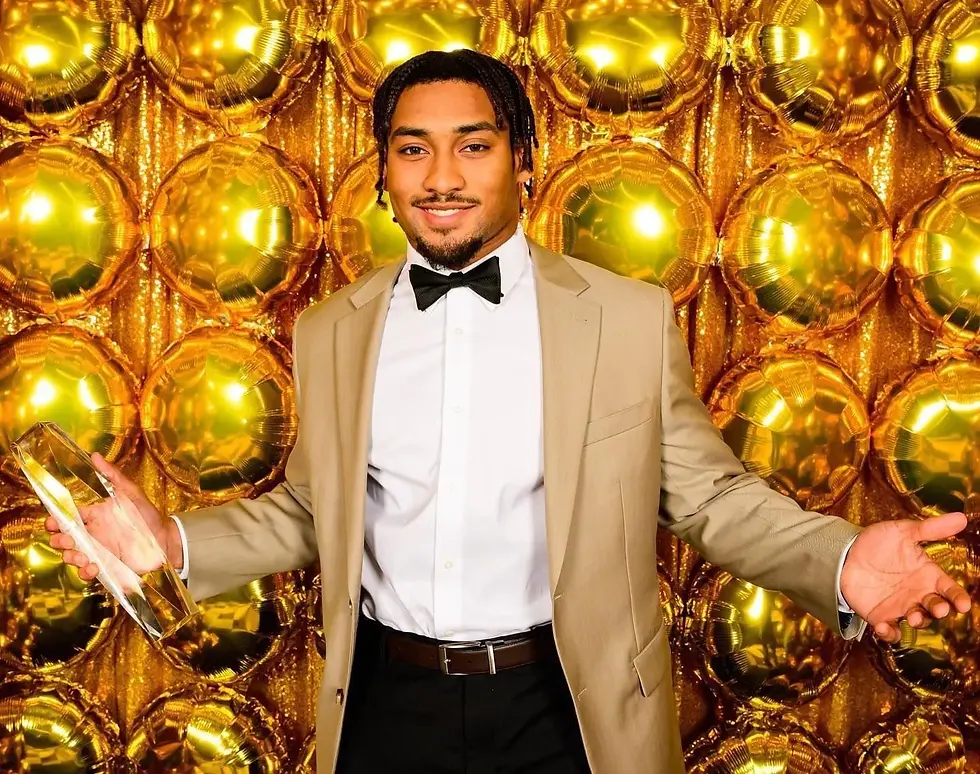 Custom gold balloon wall at LSU football awards in Baton Rouge. Football player posed in front of balloon wall for photo. 