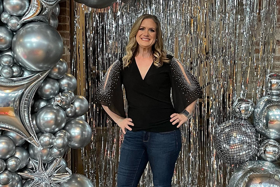 Tabtha miller, owner of animated art standing in front of a silver photo backdrop with silver balloons.
