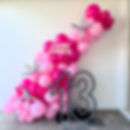 Pink birthday balloons in an organic garland with LED numbers.