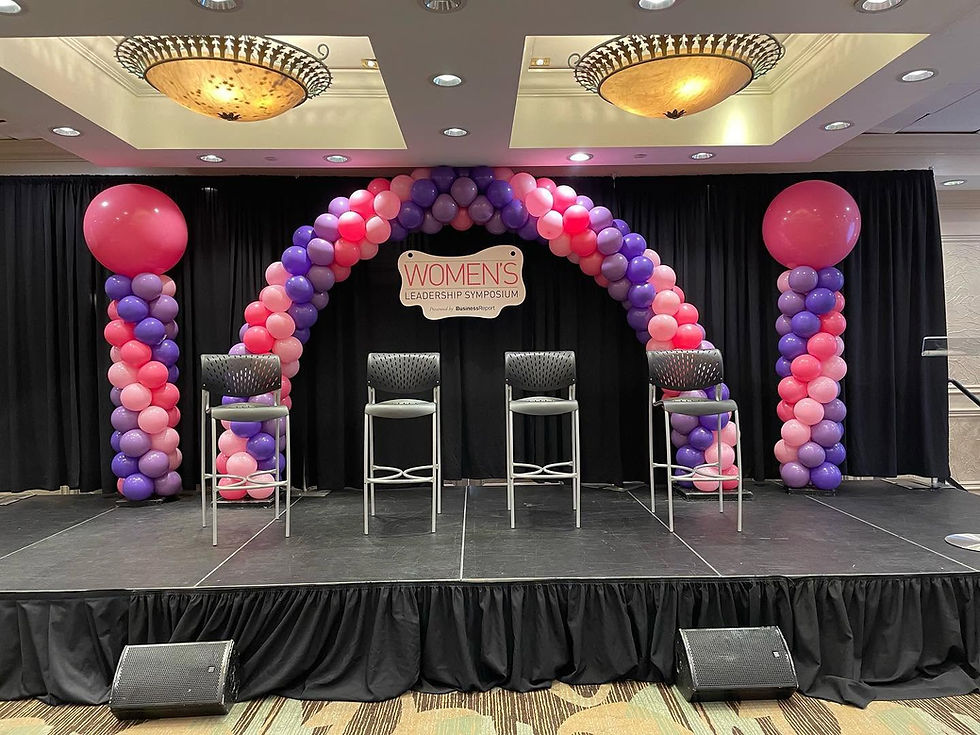 Pink and purple balloon arch with two balloon columns on each side at a conference.