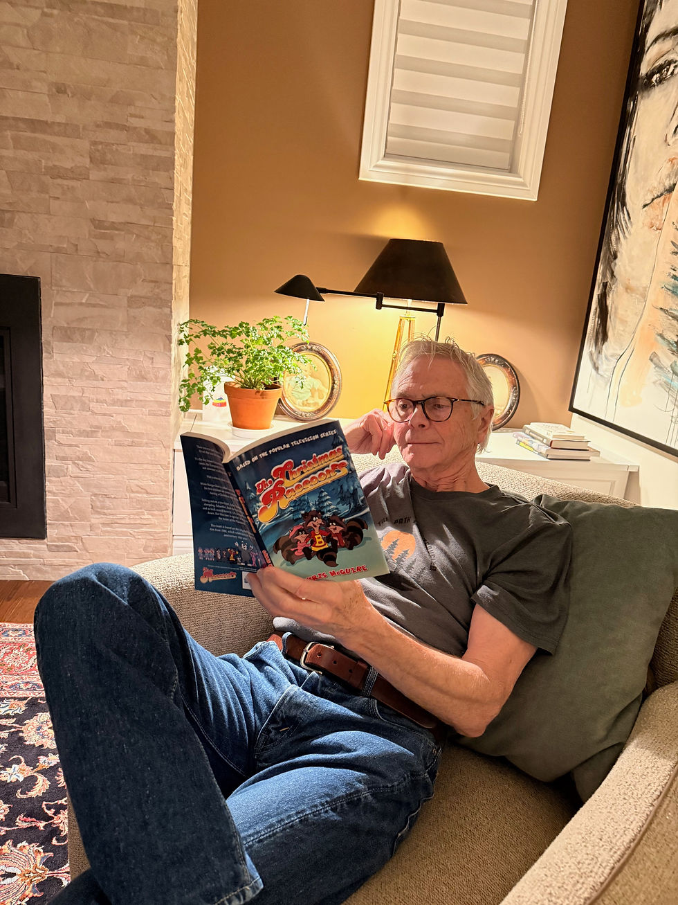 Kevin relaxing in a chair reading "Christmas Raccoons" by Chris McGuire