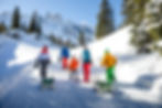 Gruppe beim Schneeschuhwandern durch einen verschneiten Bergwald im Montafon