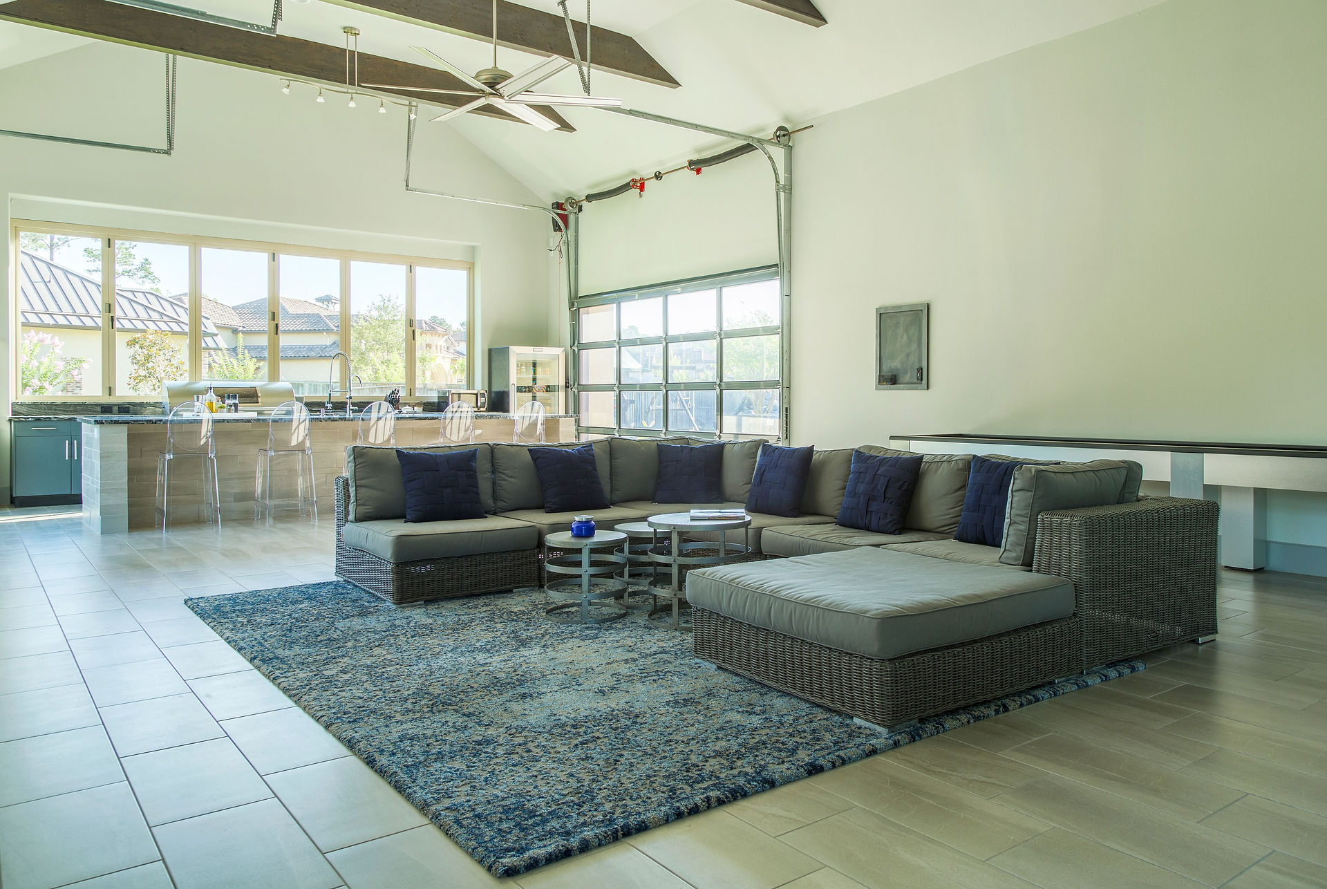 indoor outdoor living area with large sectional and outdoor kitchen and grill, barstools