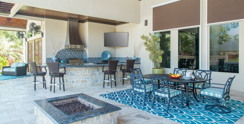 A backyard patio with outdoor kitchen, grill with a vent hood, fire pit, bar seating, dining table seating