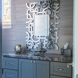 Powder bathroom in Spring, TX featuring metallic wallpaper, granite countertops, and an artistic silver mirror by By Design Interiors.