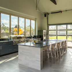 indoor and outdoor kitchen with grill, island, barstools