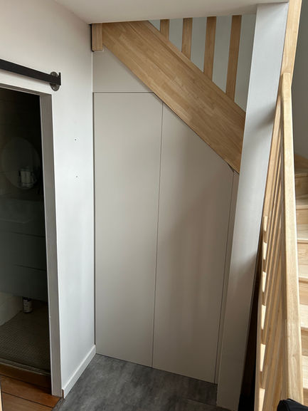 Aménagement sous escalier et installation des portes de placard pour optimiser l'espace de manière pratique et esthétique.