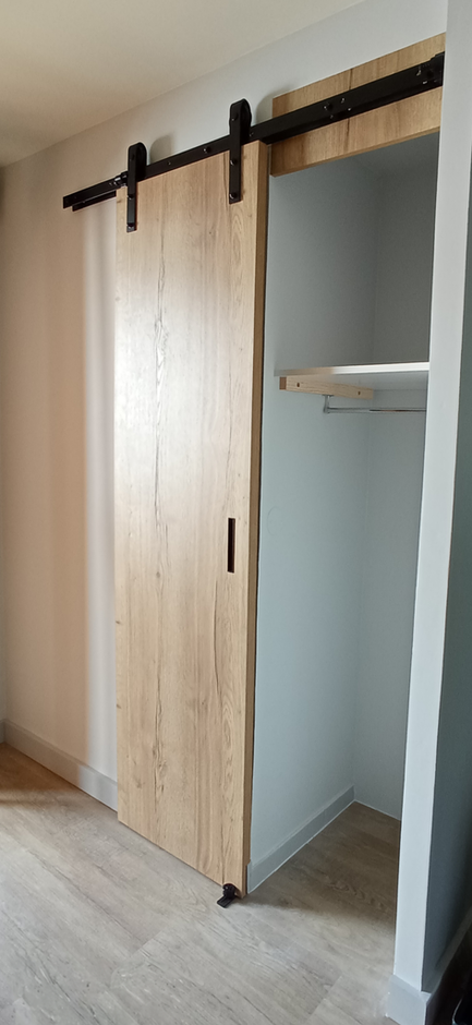 Création d'un placard de rangement avec une porte coulissante au décor en chêne, offrant à la fois praticité et élégance à l'espace.