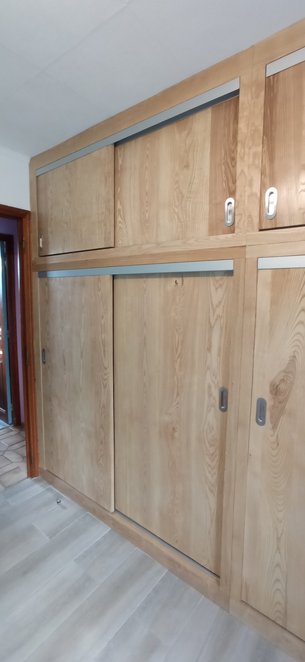 Fabrication sur mesure et pose de façades de placard en frêne massif, alliant élégance et solidité pour les rangements.