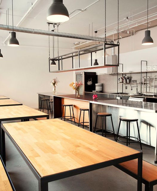 Une cuisine moderne avec des tables en bois et des luminaires suspendus.