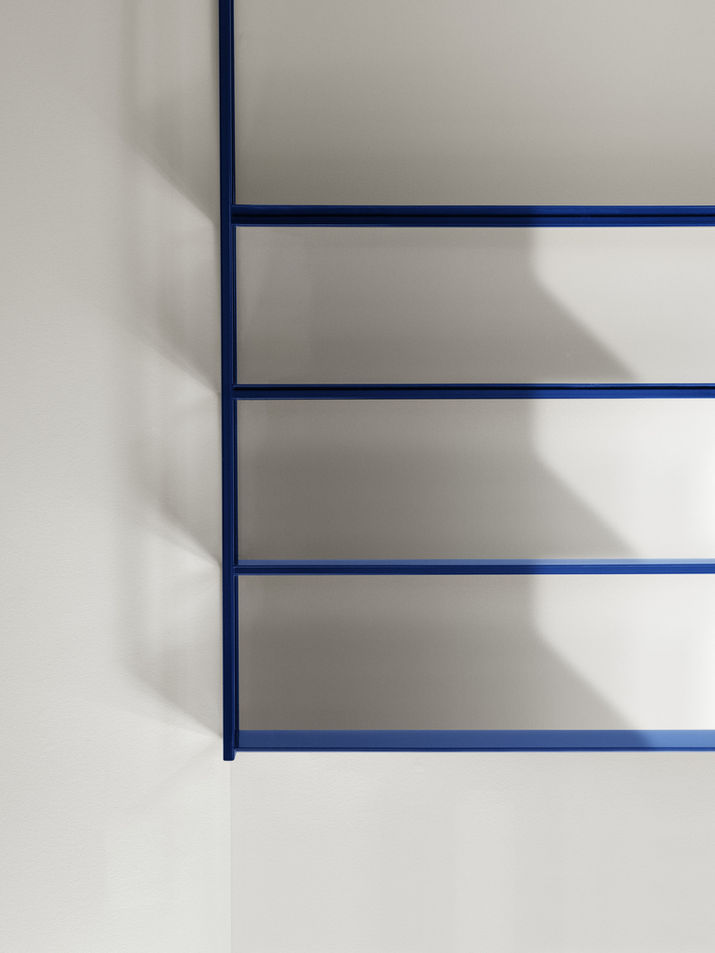 Étagère bleue avec des lignes horizontales sur un mur blanc, SOLIDO.