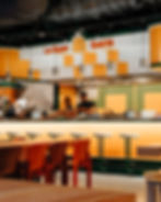 Restaurant Le Super Qualité, bar et personnes. Arrière-plan, décoration jaune et blanche, tables.