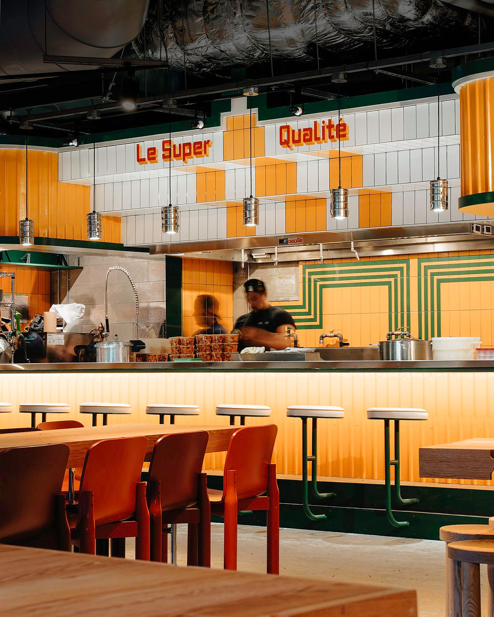 Restaurant Le Super Qualité, bar et personnes. Arrière-plan, décoration jaune et blanche, tables.