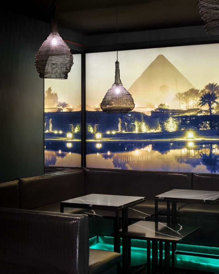 Intérieur de restaurant avec des tables et une vue sur les pyramides d'Égypte.
