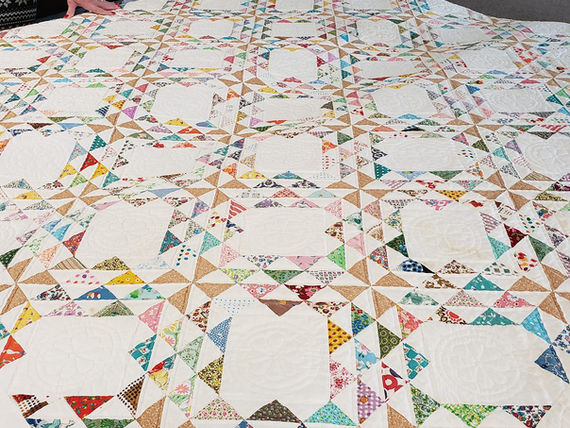 A photo of a colorful quilt, photographed at an angle as it sits on a taable.