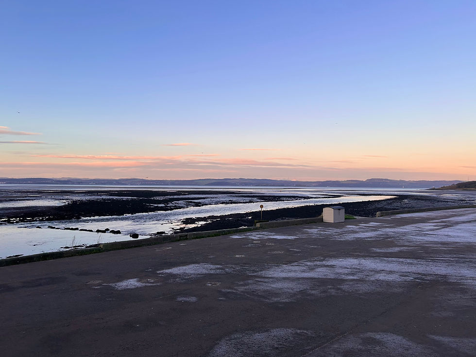 Cramond Beach in the morning. No people, sun is rising. There are hills seen in the background. 