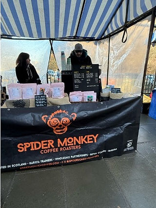 A stand with Spider Monkey written on it. Two people are serving