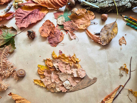 Finished cardboard hedgehog covered in autumn leaves, surrounded by natural craft materials