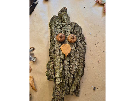 Bark owl craft with acorn cup eyes and an autumn leaf beak