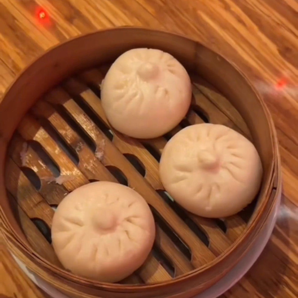 three steamed buns served in a wooden steam basket