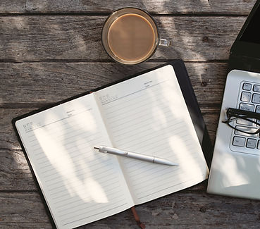 Laptop and open journal on a table in natural light, representing remote work and daily planning while traveling