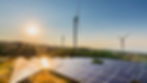 Solar-panel-array-and-wind-turnbones-on-hills-with-parched-grass-and-corse-trees-and-hedge