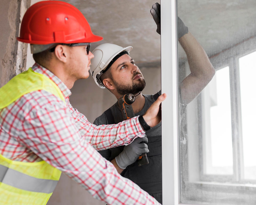 Deux hommes, l'un portant un casque rouge et l'autre un casque blanc, sont en train de fixer une vitre.