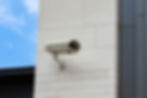 Une caméra blanche installée sur la façade extérieure blanche d'une maison.