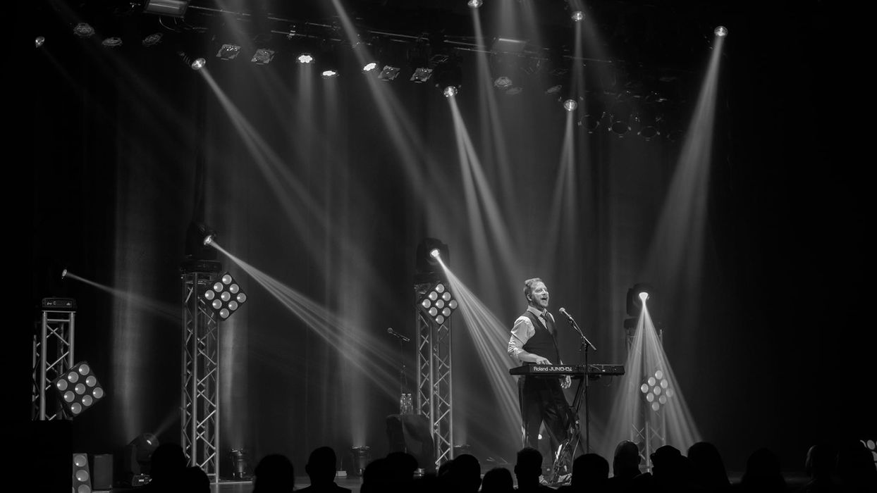 Dave Gaudet lors d'un spectacle humoriste, capté sous les projecteurs en pleine performance.