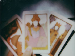 a polaroid of a hand holding 3 tarot cards