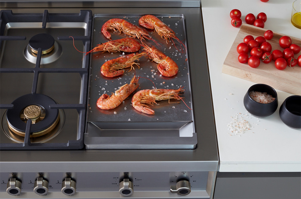 Camarões grelhados no fogão, tomates cereja e temperos na cozinha.