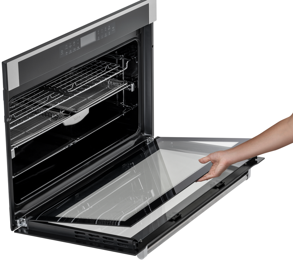 Uma mão abre a porta de vidro do forno. Prateleiras e detalhes.