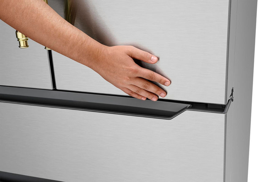 Mão abre a gaveta de inox de um refrigerador Tecno vintage.