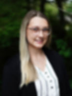 Blonde woman with glasses smiling, professional headshot against a green background.