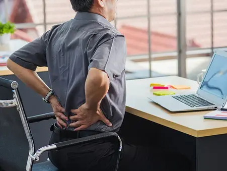 A man experiencing lower back pain from prolonged sitting
