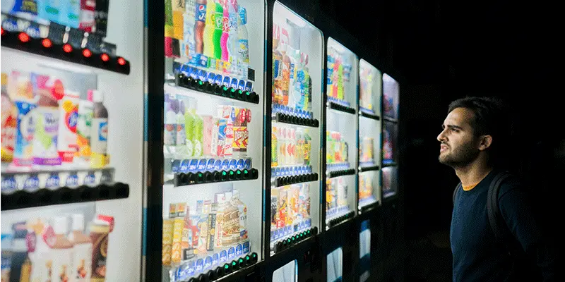 Picture of a man looking at a row of refrigerated vending machines in India