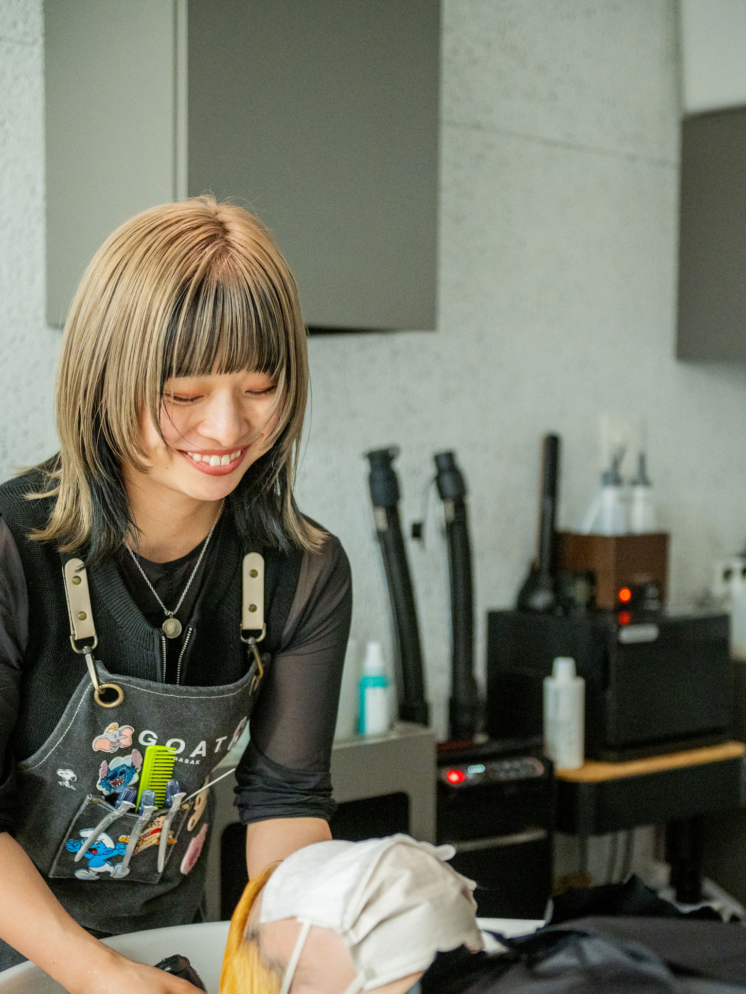 笑顔で髪を洗ってる女性スタイリスト