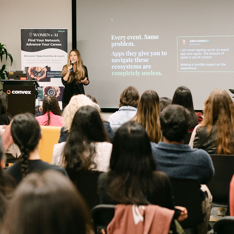 A female founder speaks at a podium to an attentive audience. A projection shows tech event critique text, set in a modern conference room.