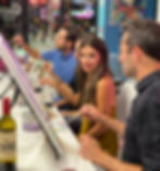 A table with adults painting on canvases