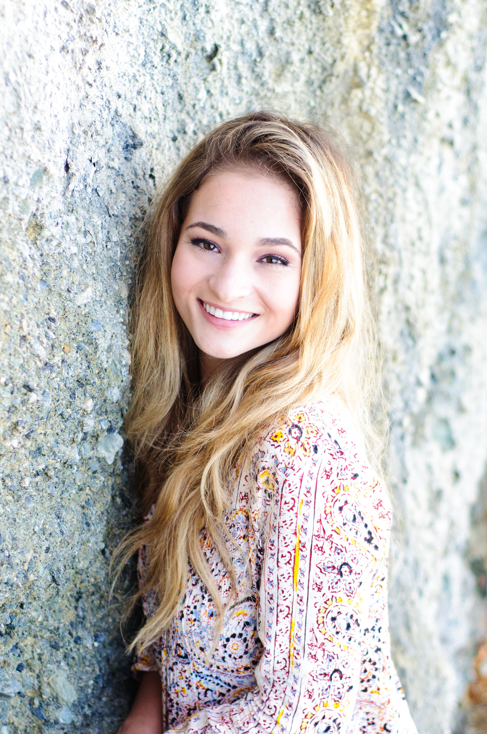 Great Oak High School senior posing against a rock wall in Laguna Beach, California