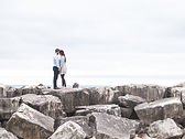 Casal em paisagem com rochas e o mar ao fundo