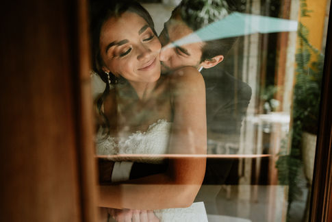 Reflejo de la pareja en el cristal mientras Sergio besa a Daniela en la mejilla.