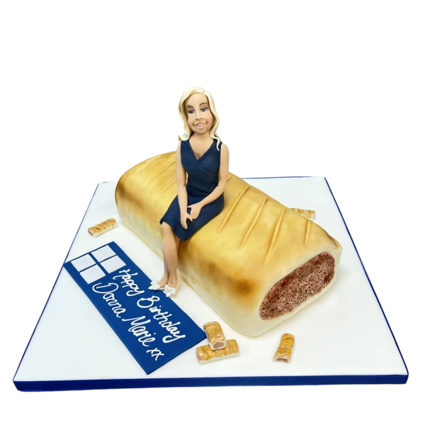 Bespoke cake shaped like a sausage roll with a lady figure, crafted for celebration in Solihull, West Midlands.
