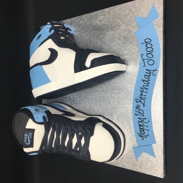 Bespoke cake shaped like Nike trainers with detailed laces and swoosh logo, crafted in Solihull, West Midlands.