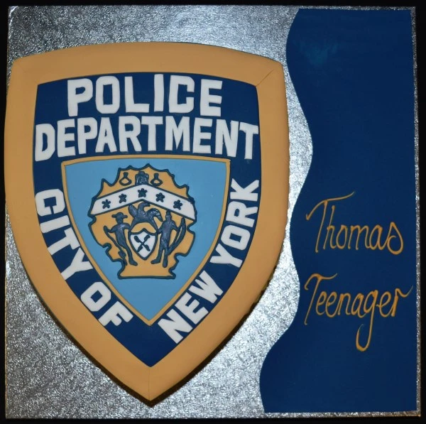 Bespoke cake shaped like a NYP police badge with detailed emblem, crafted in Solihull, West Midlands for celebration.